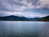 a lake with mountains in the background under a cloudy sky