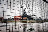 a metal fence with a view of a factory