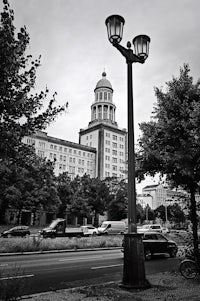 a black and white photo of a lamppost in front of a building