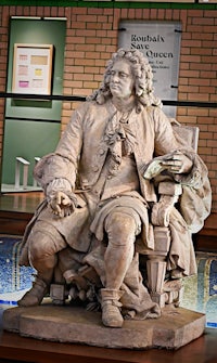 a statue of a man sitting in front of a brick wall