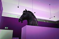 a statue of a horse in a room with purple lights