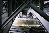 a person riding a skateboard under a bridge