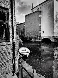 black and white photo of a boat docked in a canal