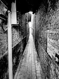 a black and white photo of a narrow alley