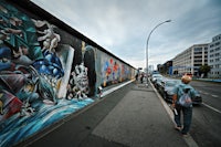 a person walking down a street with a mural on the wall